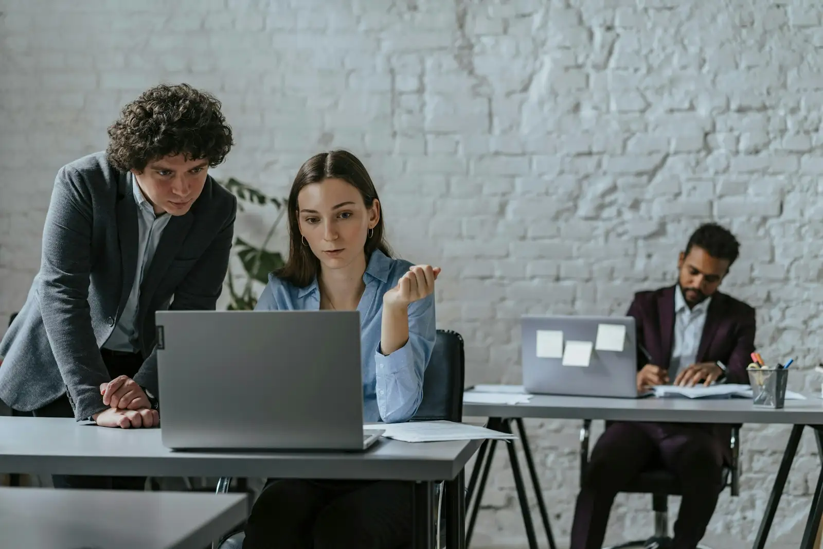 Colegas trabalhando juntos em um notebook em um escritório.