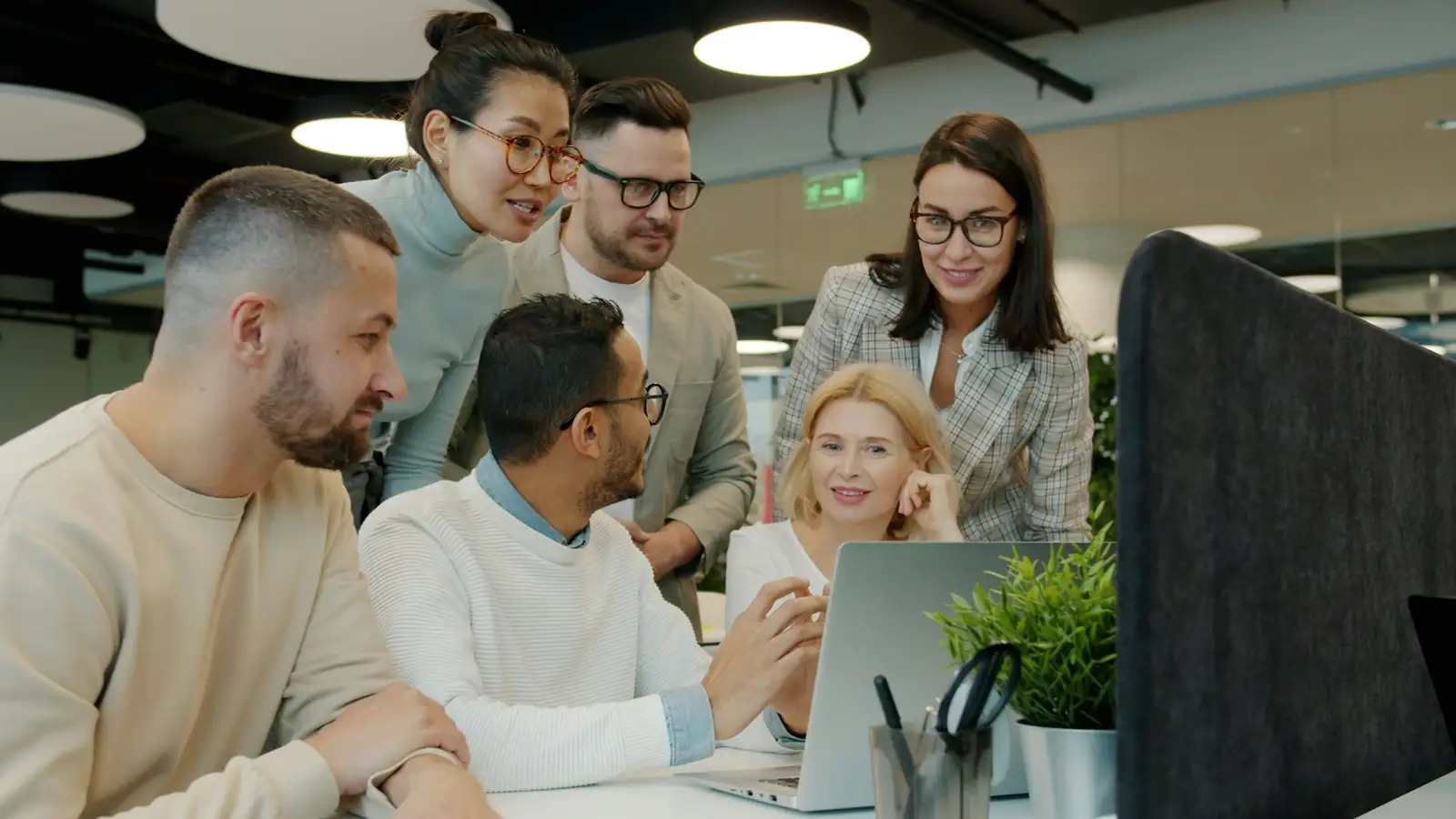 Equipe reunida em volta de um notebook em um escritório com plantas.