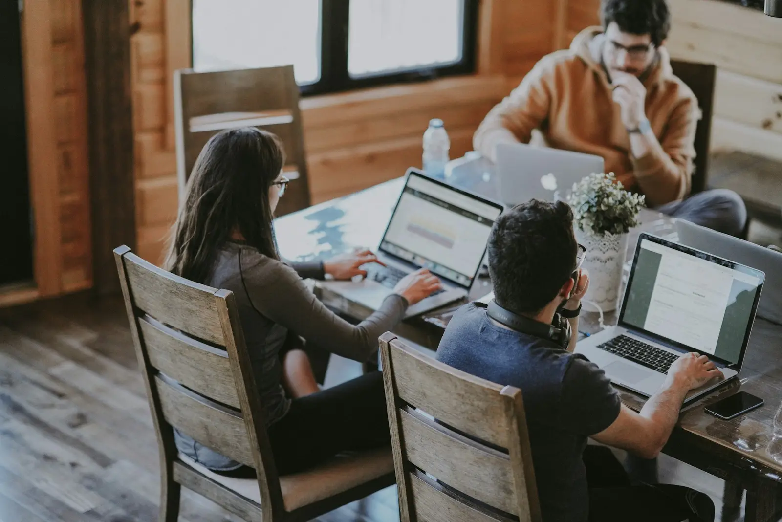 Equipe trabalhando com notebooks em uma mesa compartilhada.